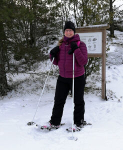 Satu Eklund nojaa lumisessa metsässä sauvoihin jalassaan lumikengät.